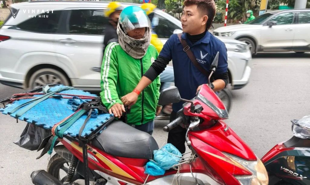 Nhân viên VinFast Huy Hiệu trao đổi với người đi xe máy xăng về chương trình chuyển đổi xe điện