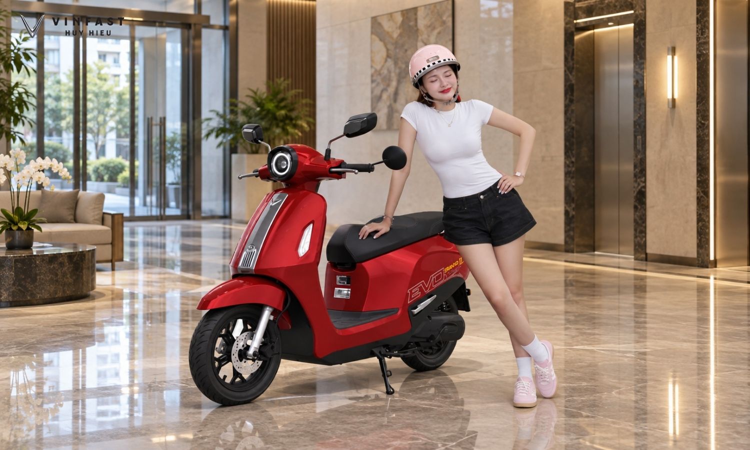 VinFast Evo Grand II màu Đỏ Ánh Kim cùng người mẫu trong sảnh